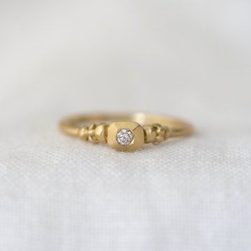 Gold ring with a diamond on a light gray background