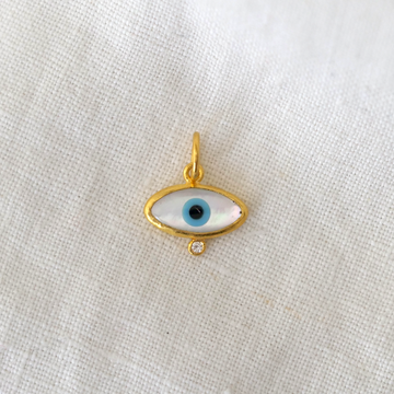 Gold pendant with eye design on a white fabric background