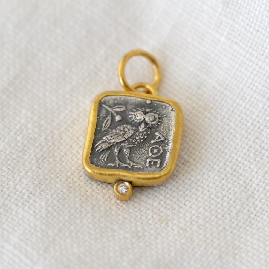 Gold and silver pendant with engraved design on a white fabric background