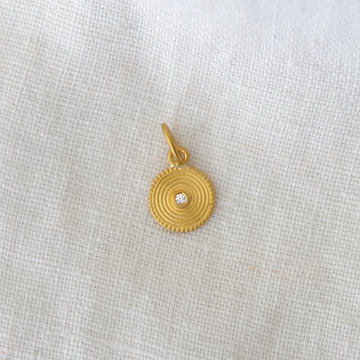 Gold pendant with a diamond on a light gray fabric background