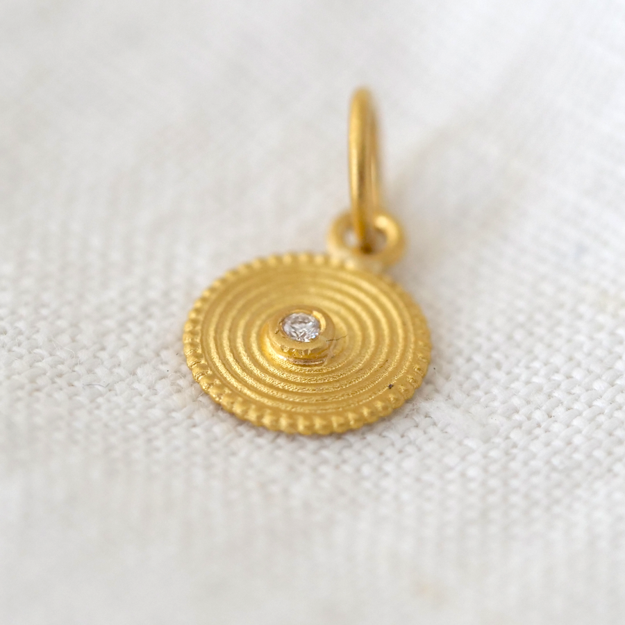 Gold pendant with a diamond on a white fabric background