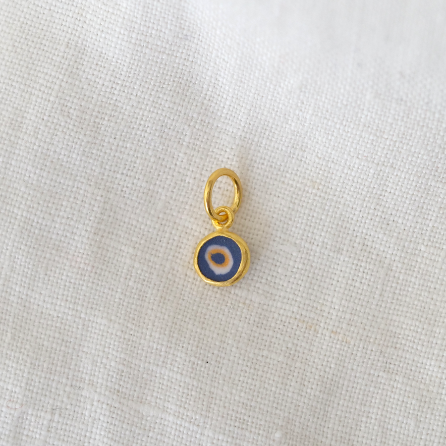 Gold pendant with a blue and white center on a light gray background
