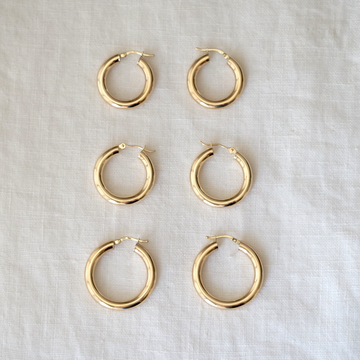 Set of gold hoop earrings on a light gray fabric background