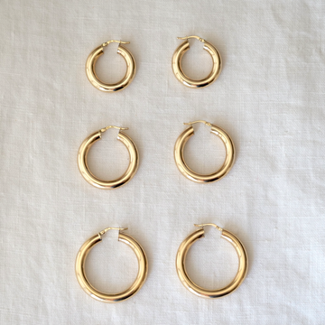 Set of gold hoop earrings on a light fabric background