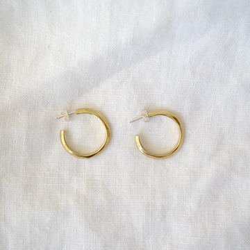 Gold hoop earrings on a white fabric background