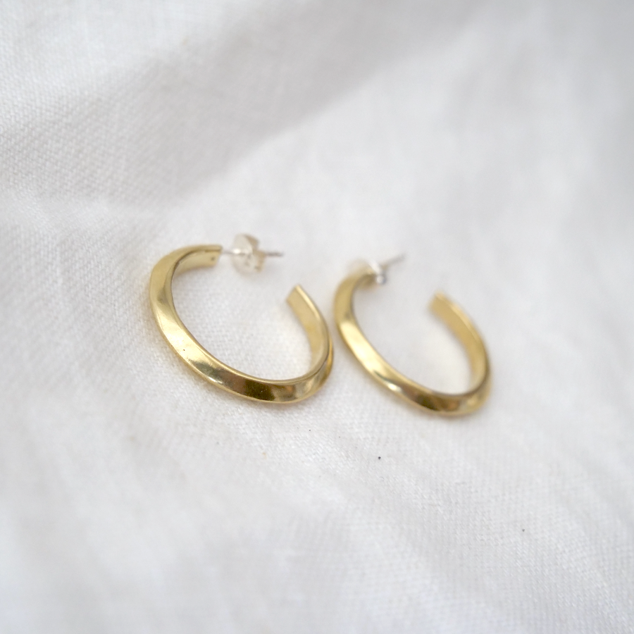 Gold hoop earrings on a white fabric background