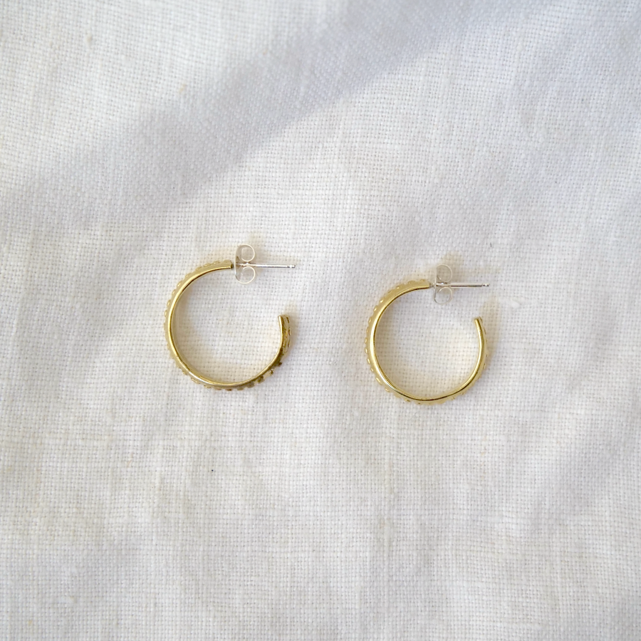 Gold hoop earrings on a light gray fabric background