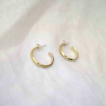 Gold hoop earrings on a white fabric background