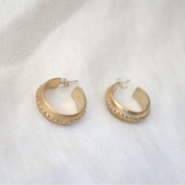 Gold hoop earrings on a white fabric background