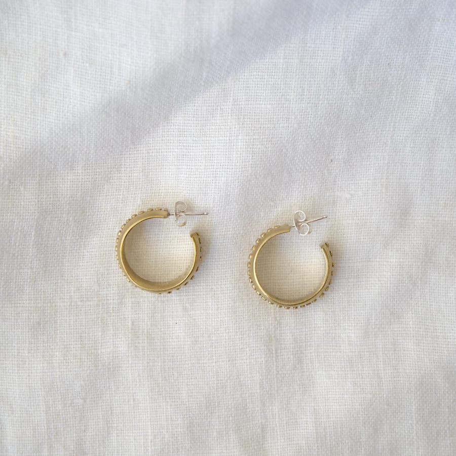 Gold hoop earrings on a white fabric background