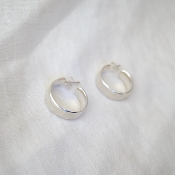 Silver hoop earrings on a white fabric background