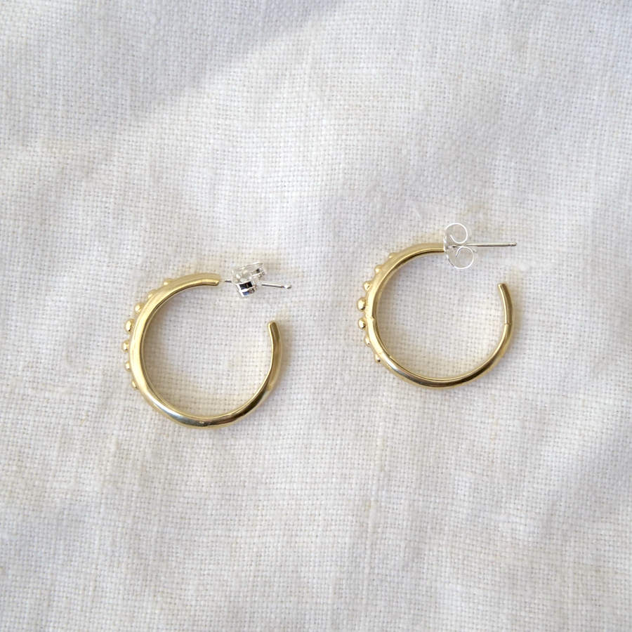 Gold hoop earrings on a light gray fabric background
