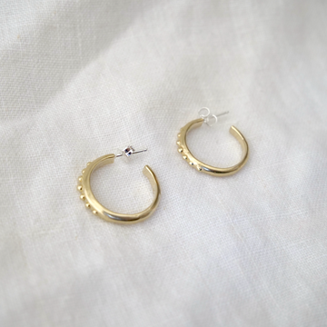 Gold hoop earrings on a light gray fabric background