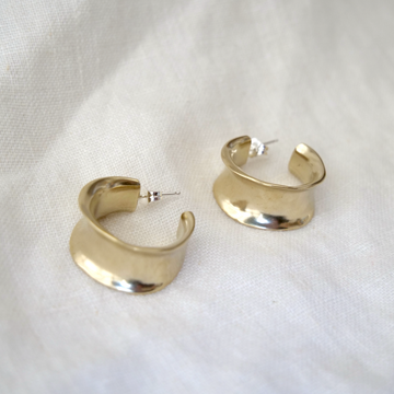Gold hoop earrings on a white fabric background