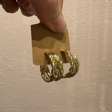 brass hoop earrings on a cardboard stand against a beige background