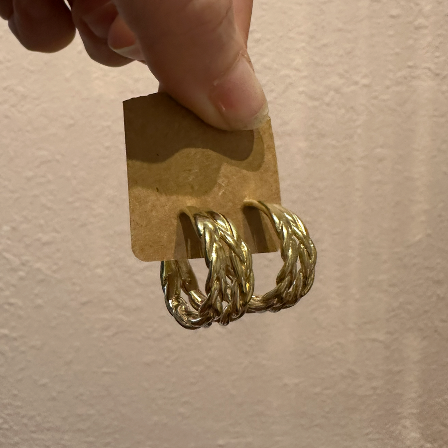 brass hoop earrings on a cardboard stand against a beige background