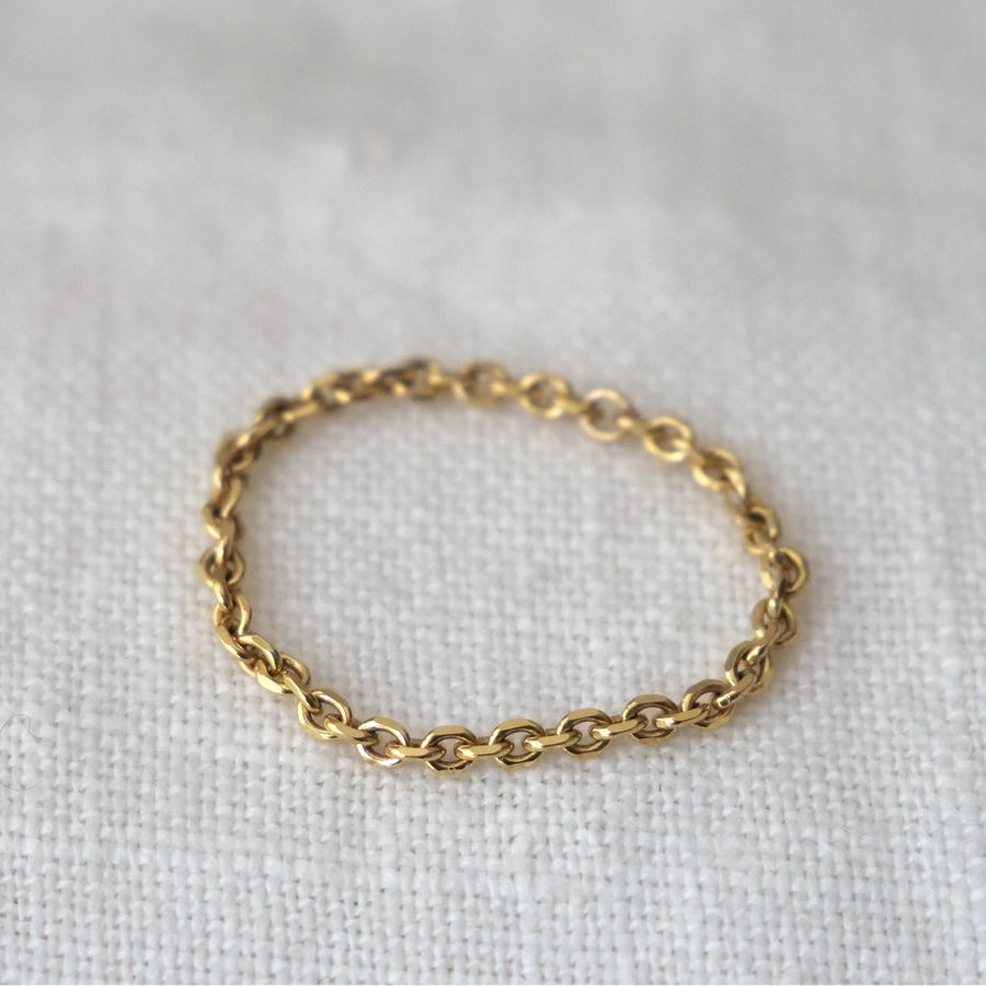 Gold chain ring on a light gray background