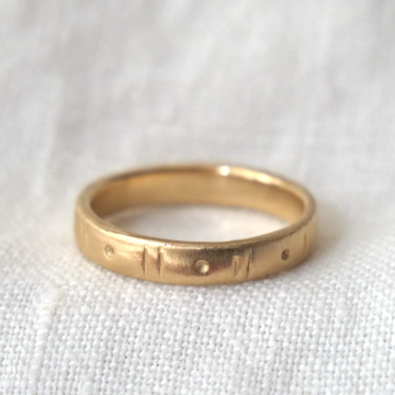 Gold ring with engraved design on a white fabric background