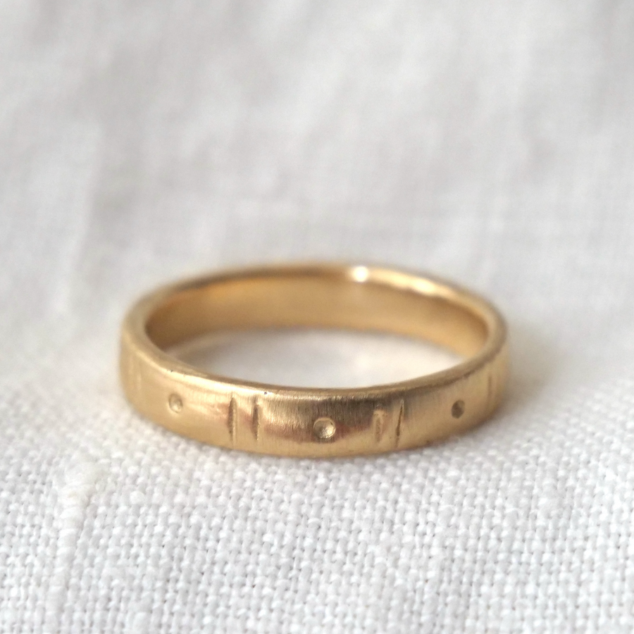 Gold ring with engraved design on a white fabric background