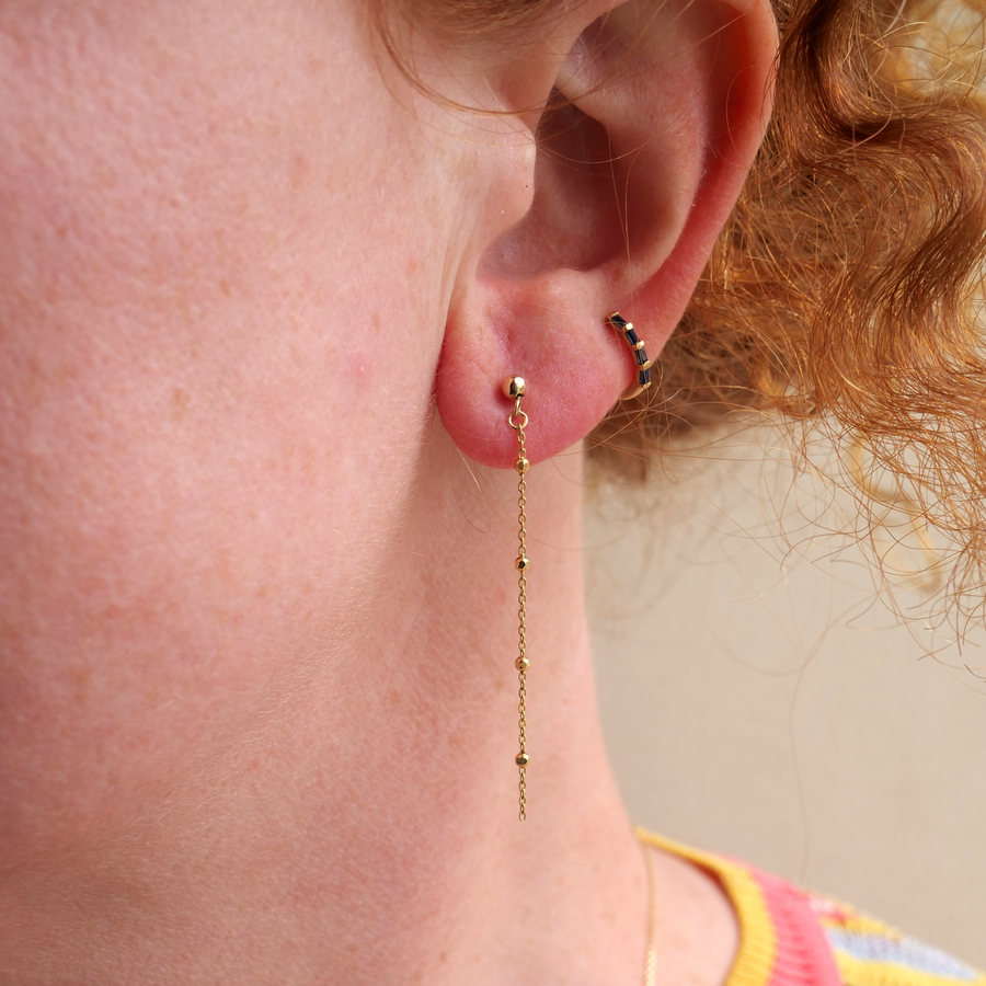 Close-up of a person wearing gold earrings with a neutral background