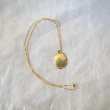 Gold necklace with an oval pendant on a light gray background