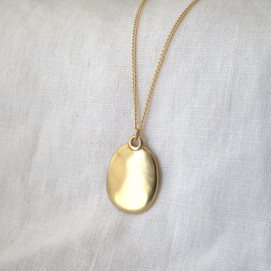 Gold necklace with a pendant on a white fabric background