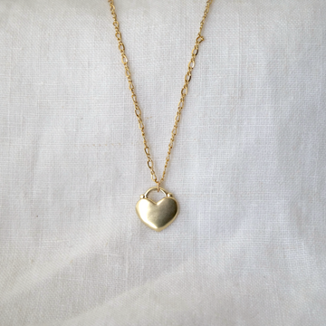 Gold heart-shaped pendant necklace on a light fabric background