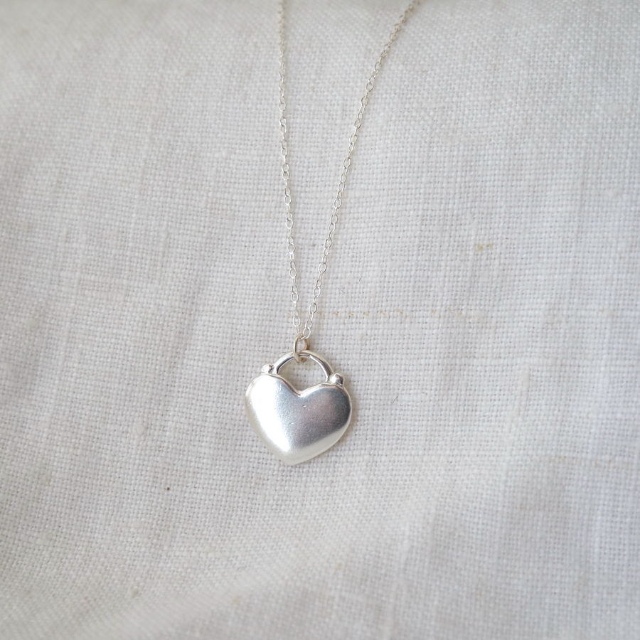 Silver heart-shaped pendant necklace on a light fabric background