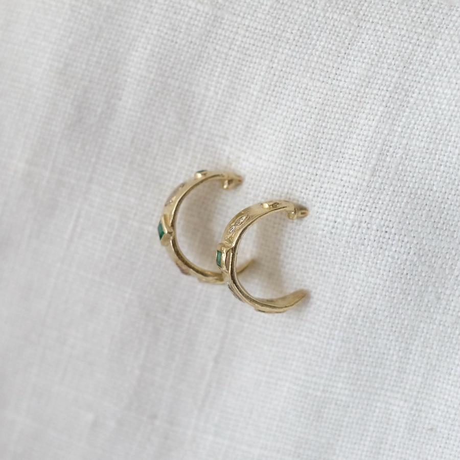 Gold hoop earrings on a white fabric background