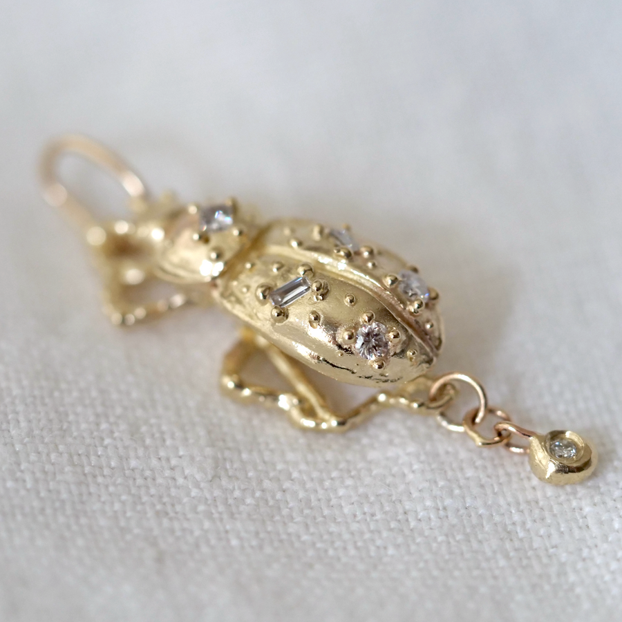 Gold pendant with diamond accents on a white fabric background