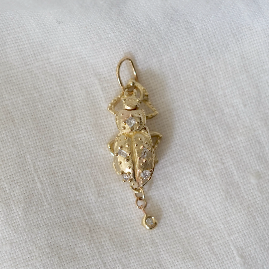 Gold pendant with intricate design on a white fabric background