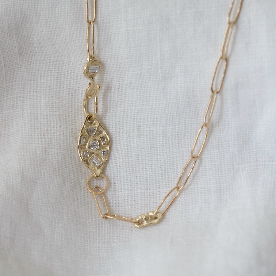 Gold chain necklace with decorative clasp on a light gray background