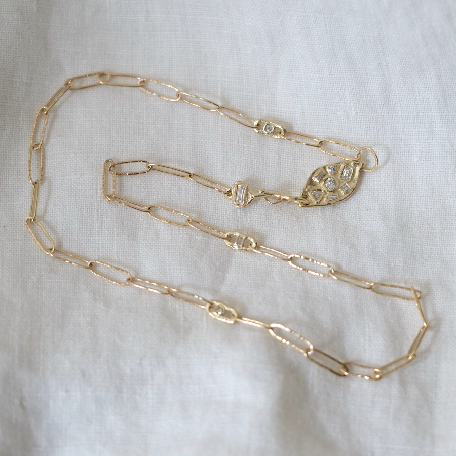 Gold chain necklace on a white fabric background