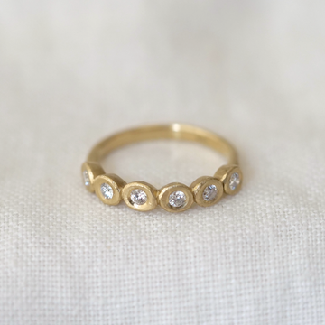Gold ring with embedded with 6 diamonds on a light fabric background