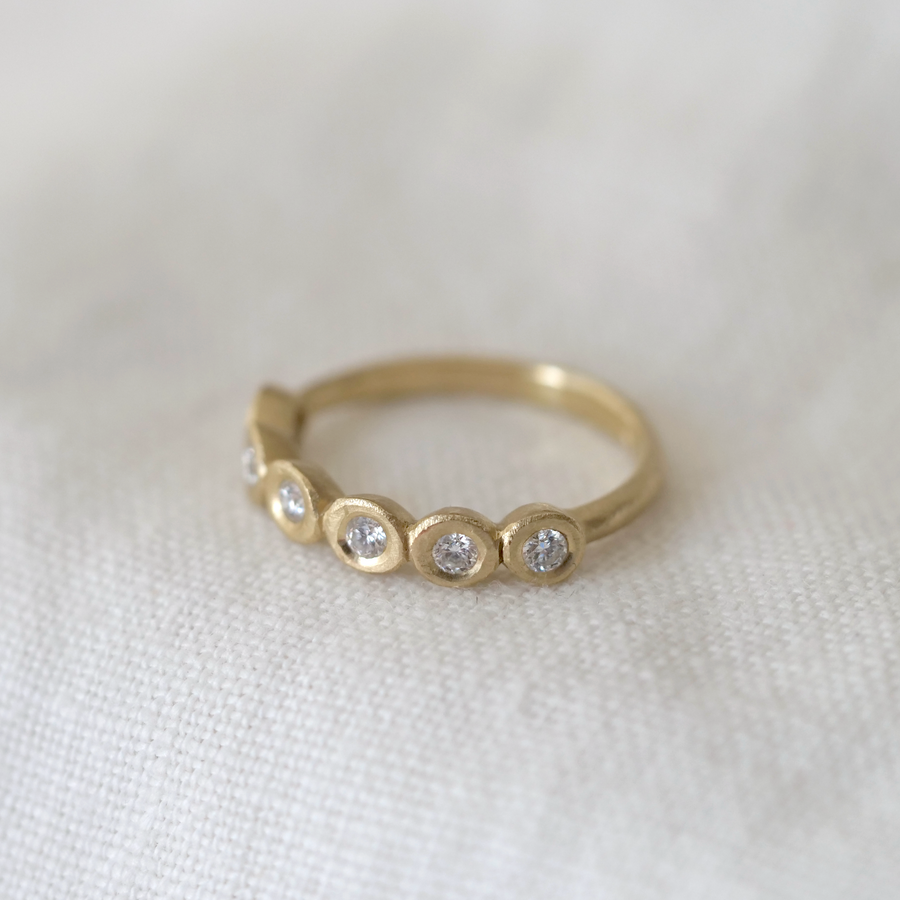 Gold ring with embedded diamonds on a white fabric background