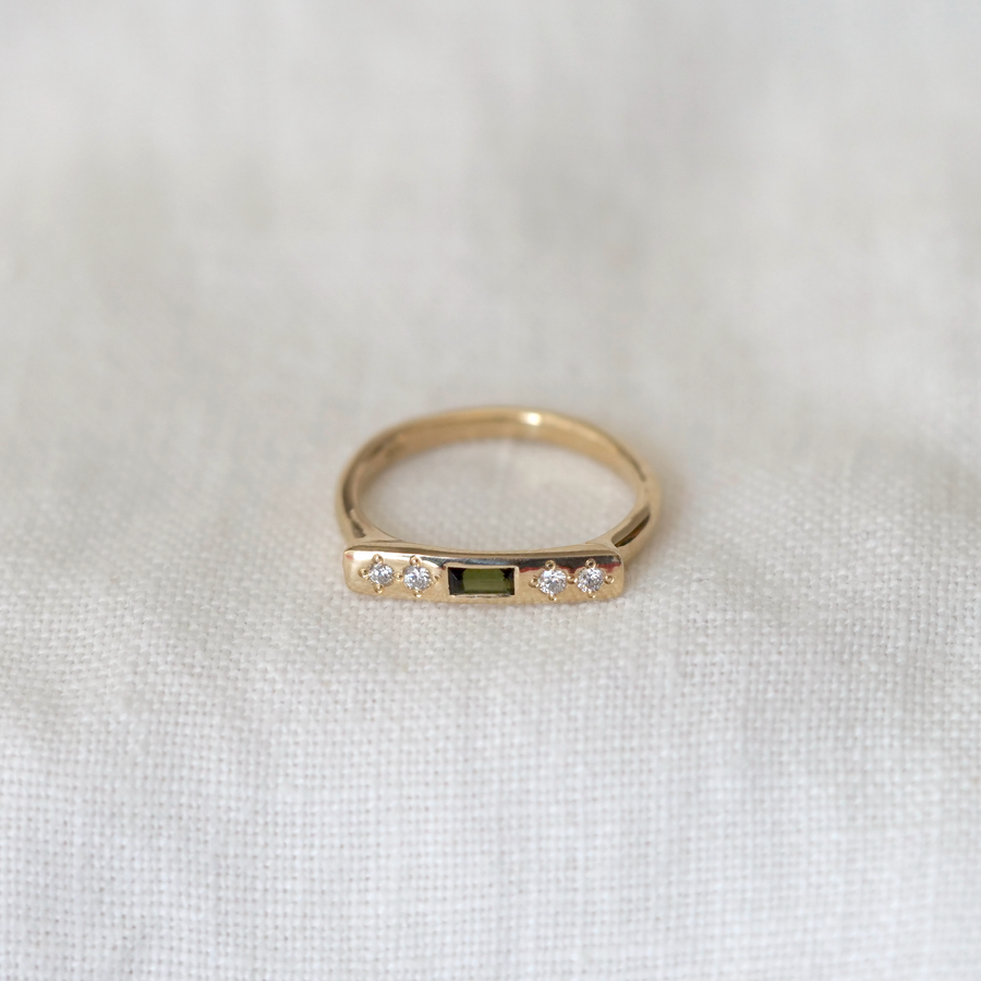 Gold ring with gemstones on a white fabric background