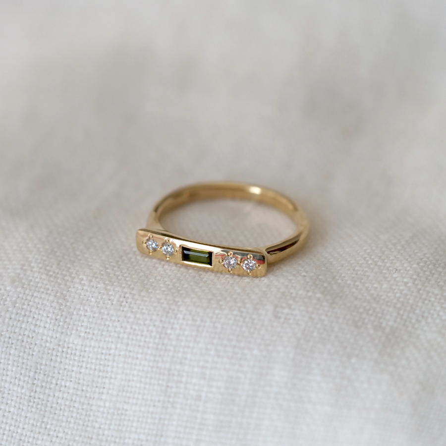 Gold ring with embedded diamonds on a light fabric background