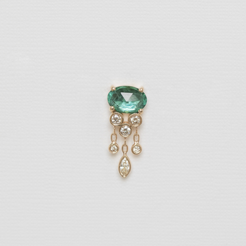 Jewelry piece with a green gemstone and dangling elements on a light gray background
