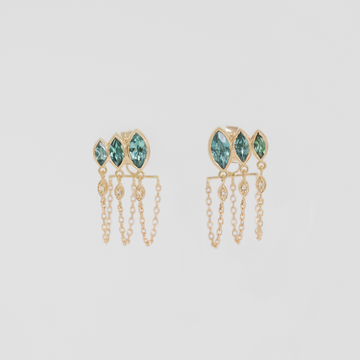 Gold earrings with three marquise cut green gemstones on a light gray background