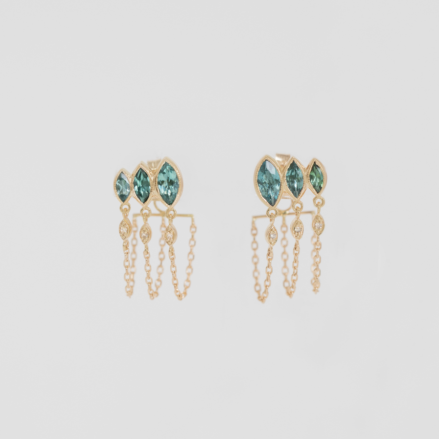 Gold earrings with three marquise cut green gemstones on a light gray background