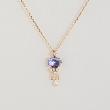 Gold necklace with a purple gemstone pendant on a light gray background