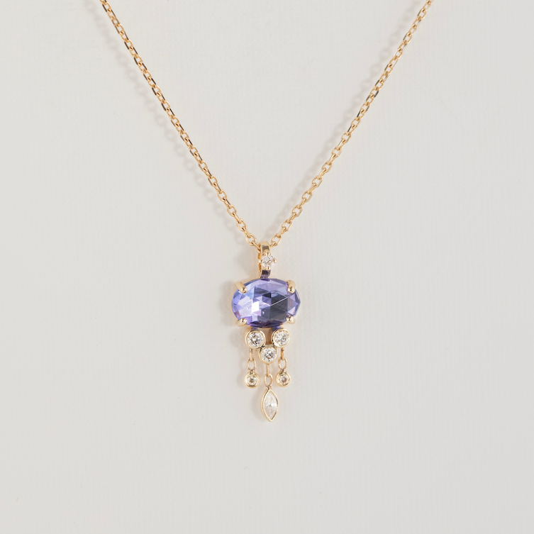 Gold necklace with a purple gemstone pendant on a light gray background