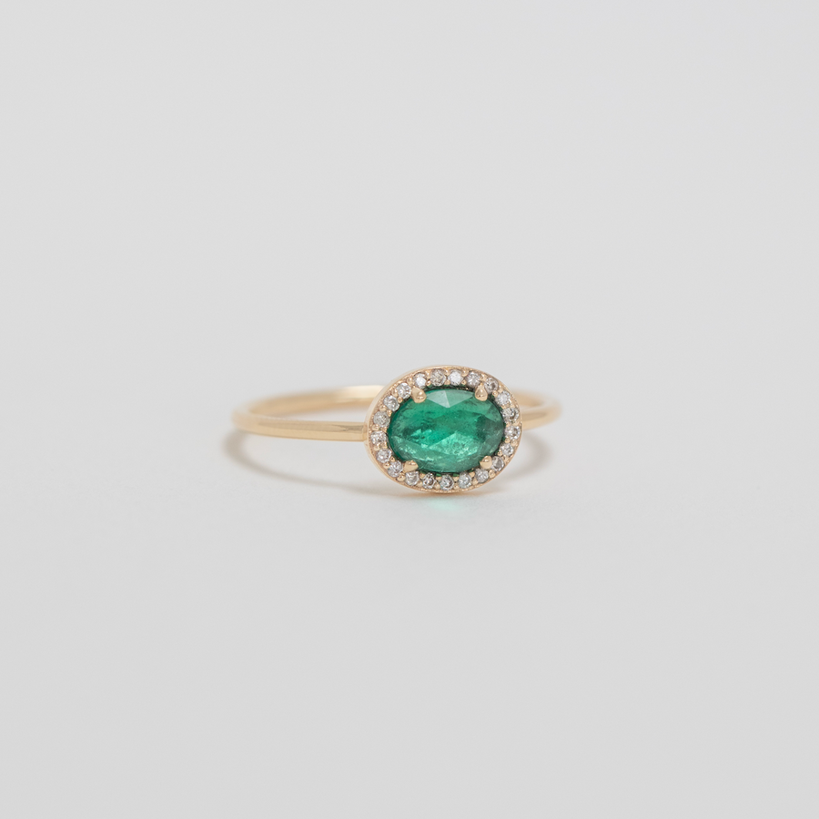 Gold ring with a green gemstone on a light gray background