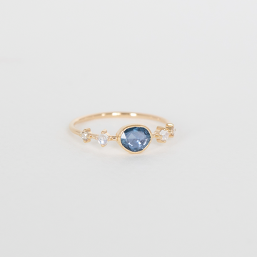 Gold ring with a blue gemstone on a light gray background