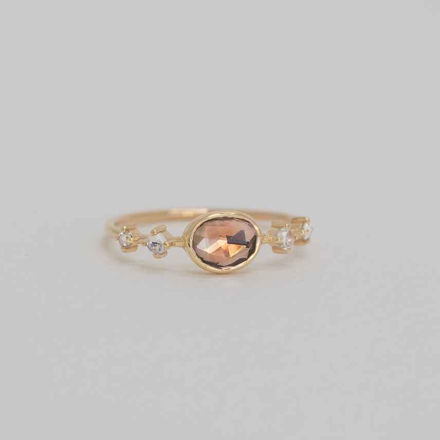 Gold ring with a brown gemstone on a light gray background