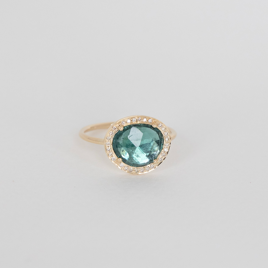 Gold ring with a green gemstone on a light gray background