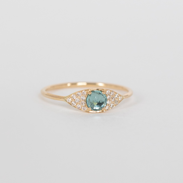 Gold ring with a blue gemstone on a light gray background