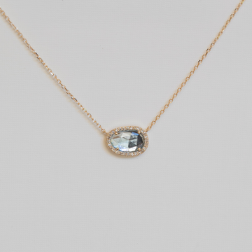 Necklace with a pendant featuring a blue gemstone on a light gray background