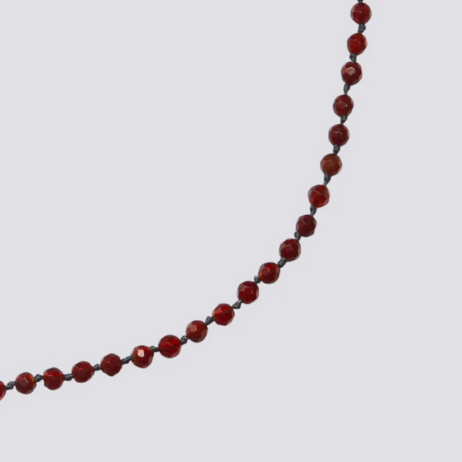 Red beaded necklace on a light gray background