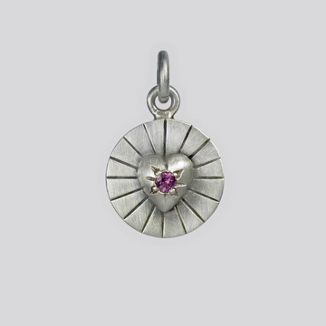 Silver pendant with a heart design and purple gemstone on a light gray background